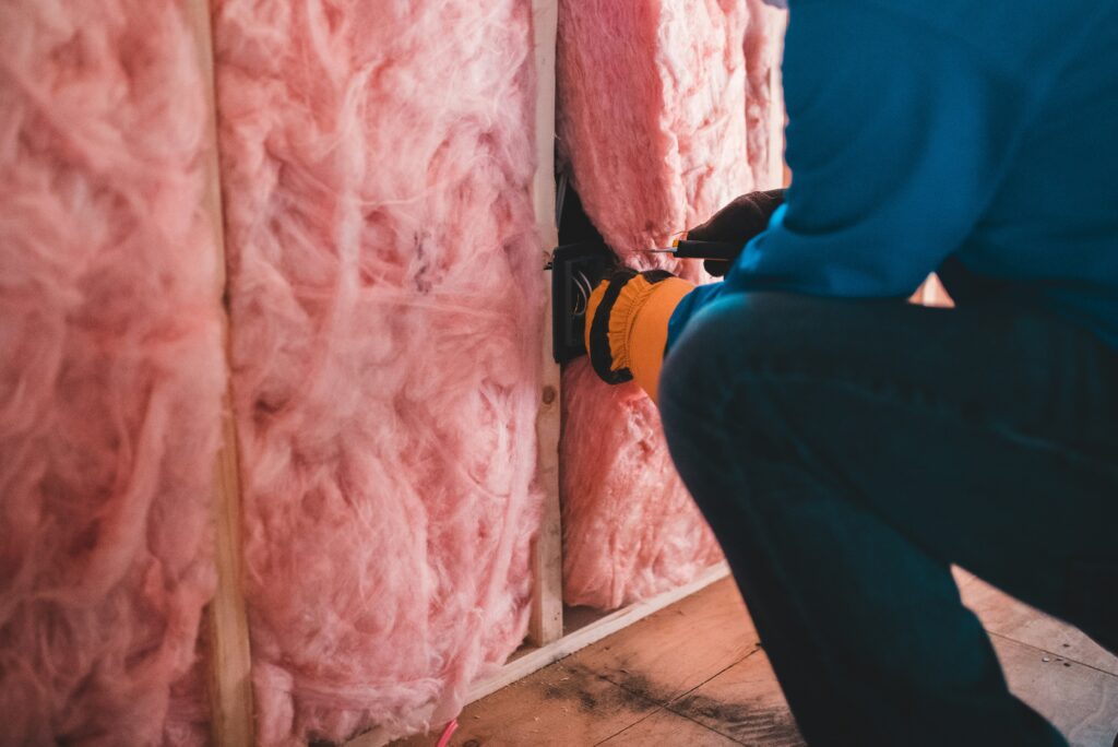 An installer pushes insulation into a stud wall